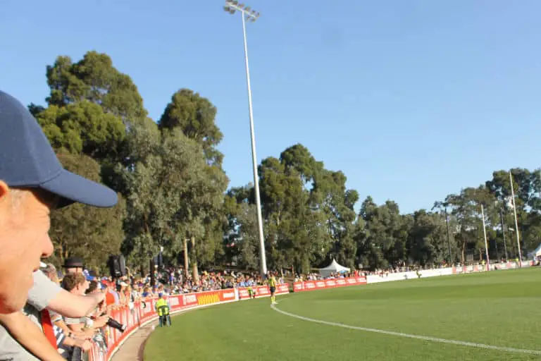 A football crowd watching an AFLW game during summer